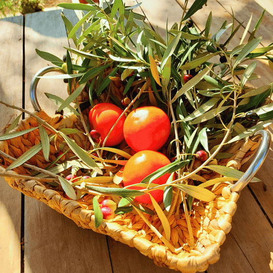 Bandeja cuadrada Da Lat de fibra natural de jacinto de agua sobre mesa de madera, en su interior tomates y olivas.