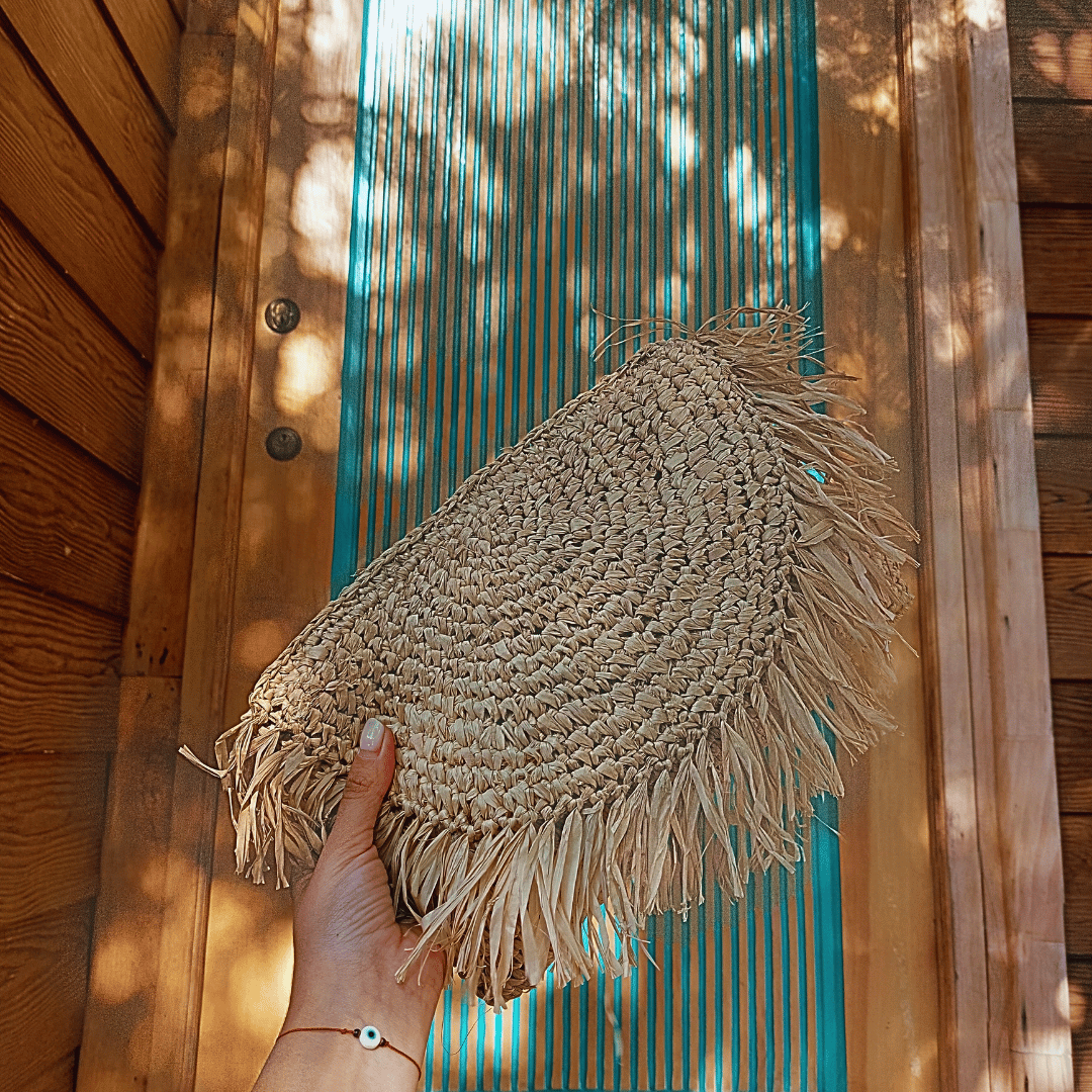 Mujer sosteniendo Cartera Clutch Kuta de rafia con la mano
