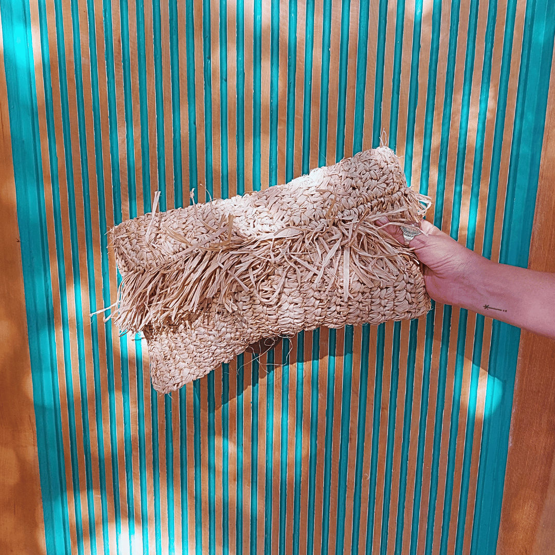 Mano sosteniendo Cartera Clutch Kuta de rafia