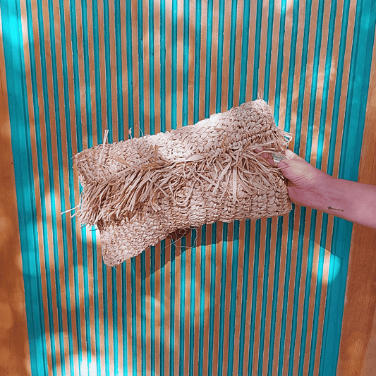 Mano sosteniendo Cartera Clutch Kuta de rafia