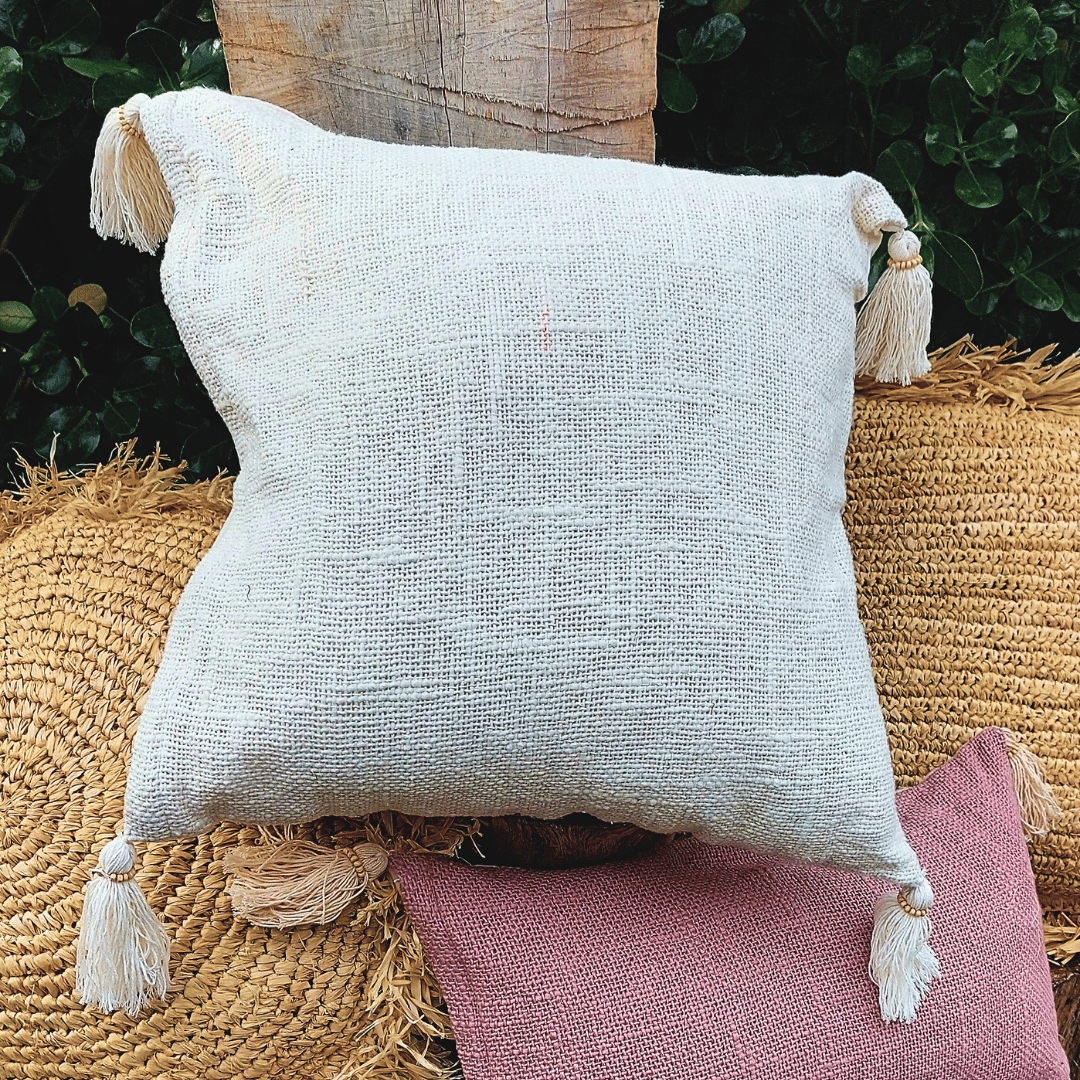 Cojín Kapas cuadrado de algodón color blanco boho sobre sofá.