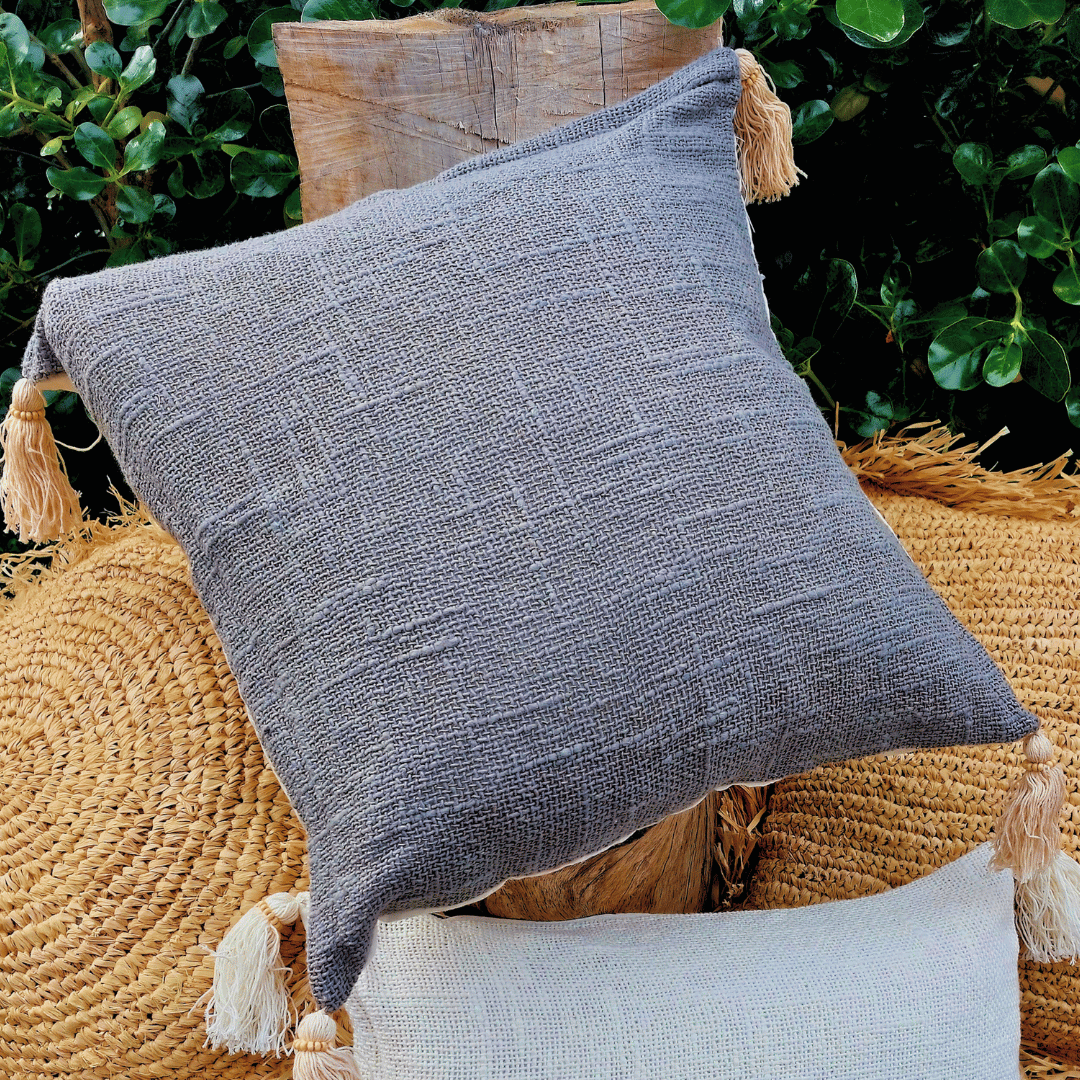 Cojín Kapas cuadrado de algodón color gris estilo boho sobre sofá.