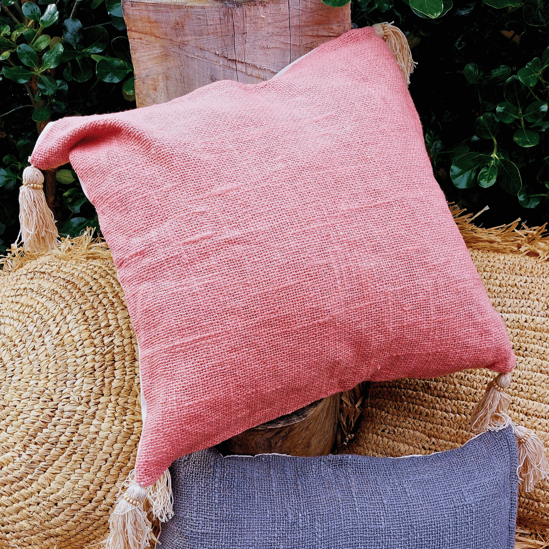 Cojín Kapas cuadrado de algodón color rosa estilo boho sobre sofá.