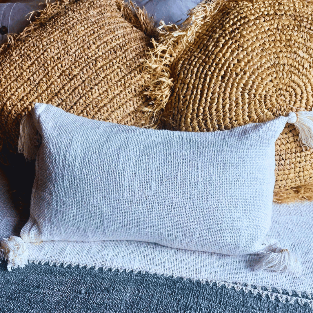 Cojín Kapas rectangular de algodón color blanco boho sobre sofá.