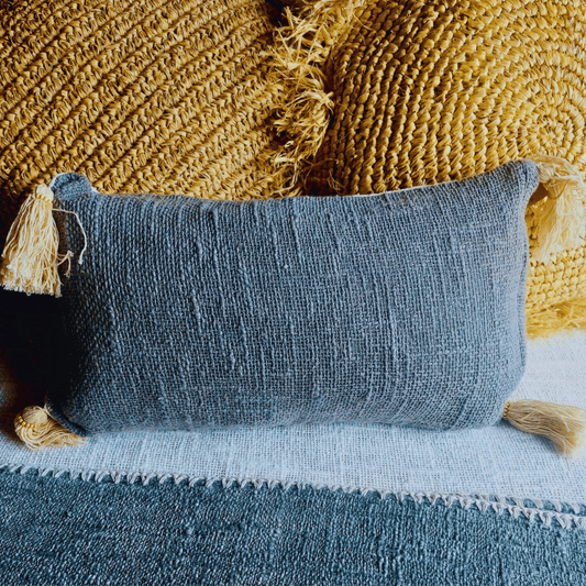 Cojín Kapas rectangular de algodón color gris estilo boho sobre cama.