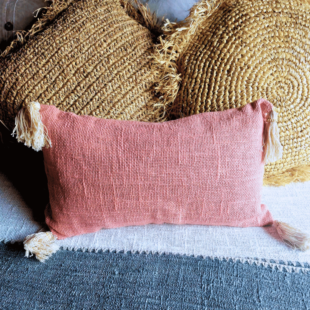 Cojín Kapas rectangular de algodón color rosa estilo boho sobre sofá.