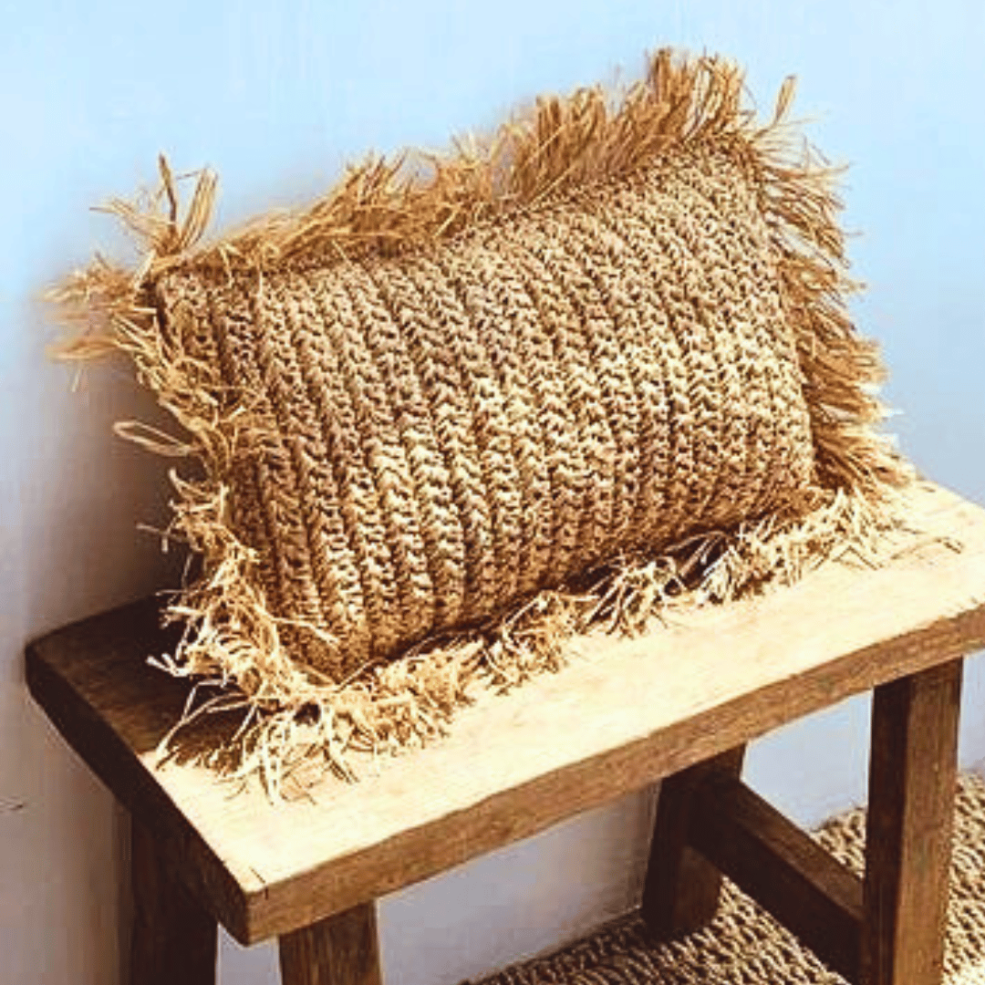 Cojín Balangan rectangular de rafia natural estilo boho sobre piso.
