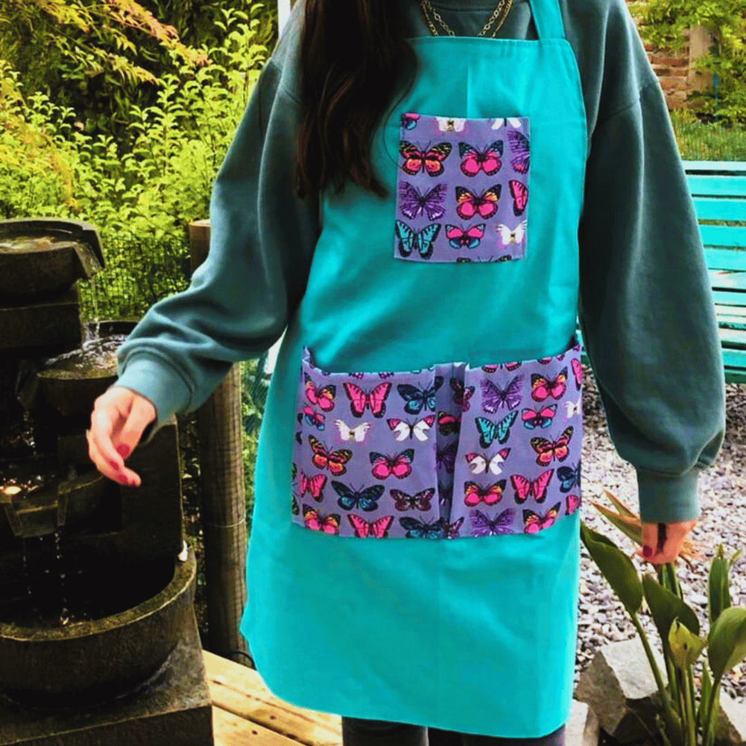 Persona usando delantal color verde de jardinería mientras trabaja en el jardín