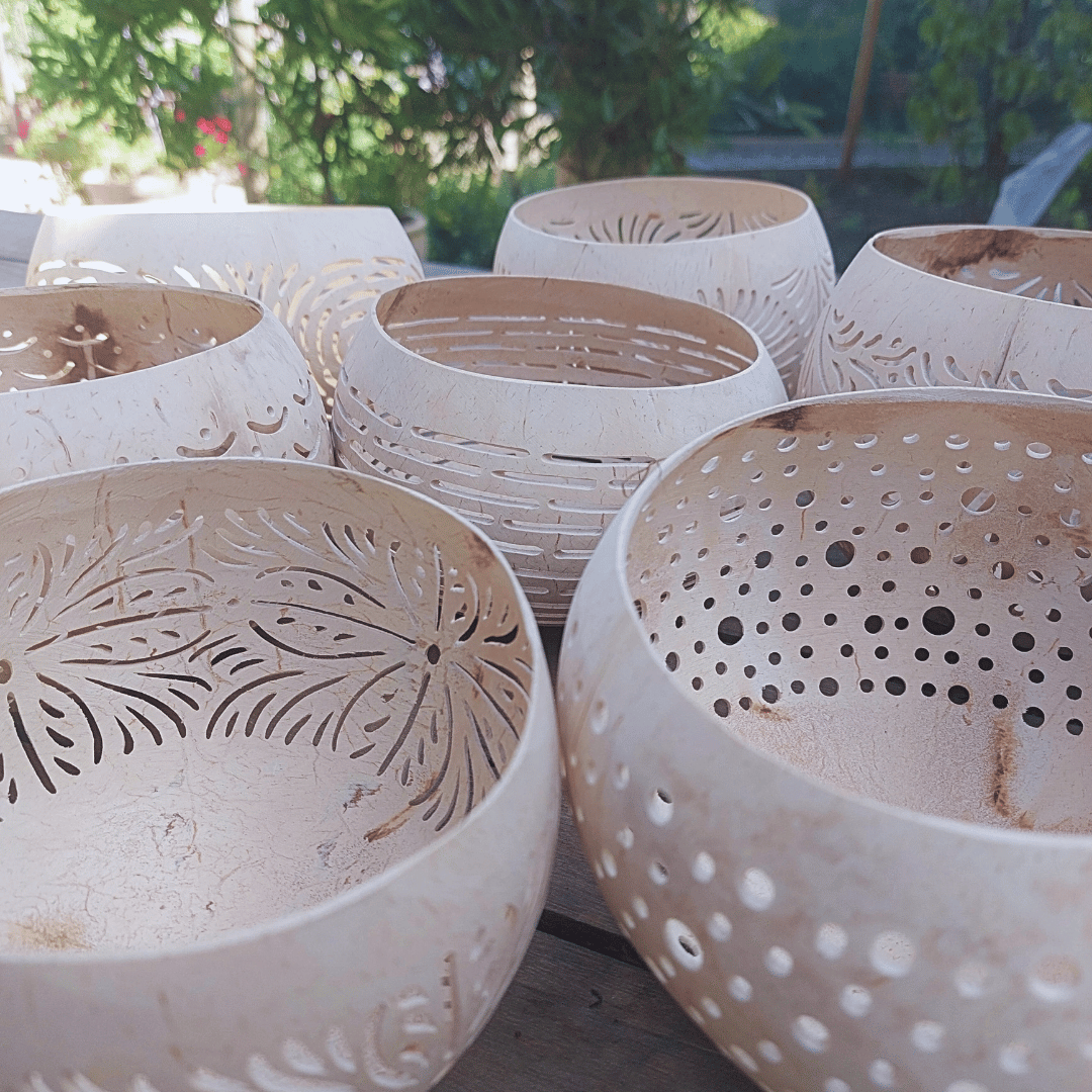Portavelas de coco artesanales con patrónes geométricos tallados.