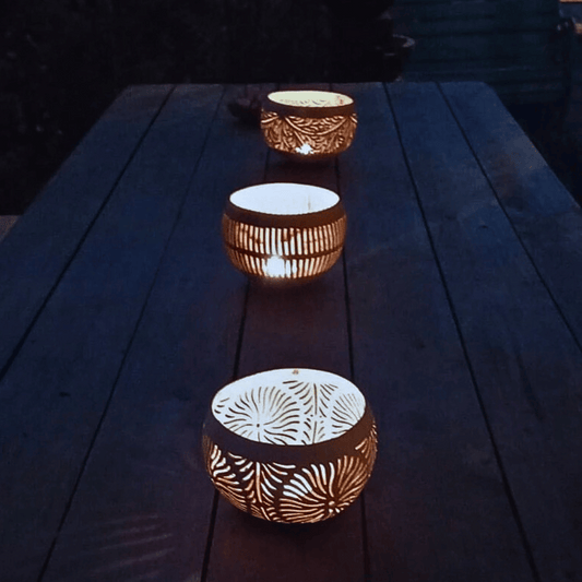 Varios portavelas de coco iluminando una mesa de centro rústica.